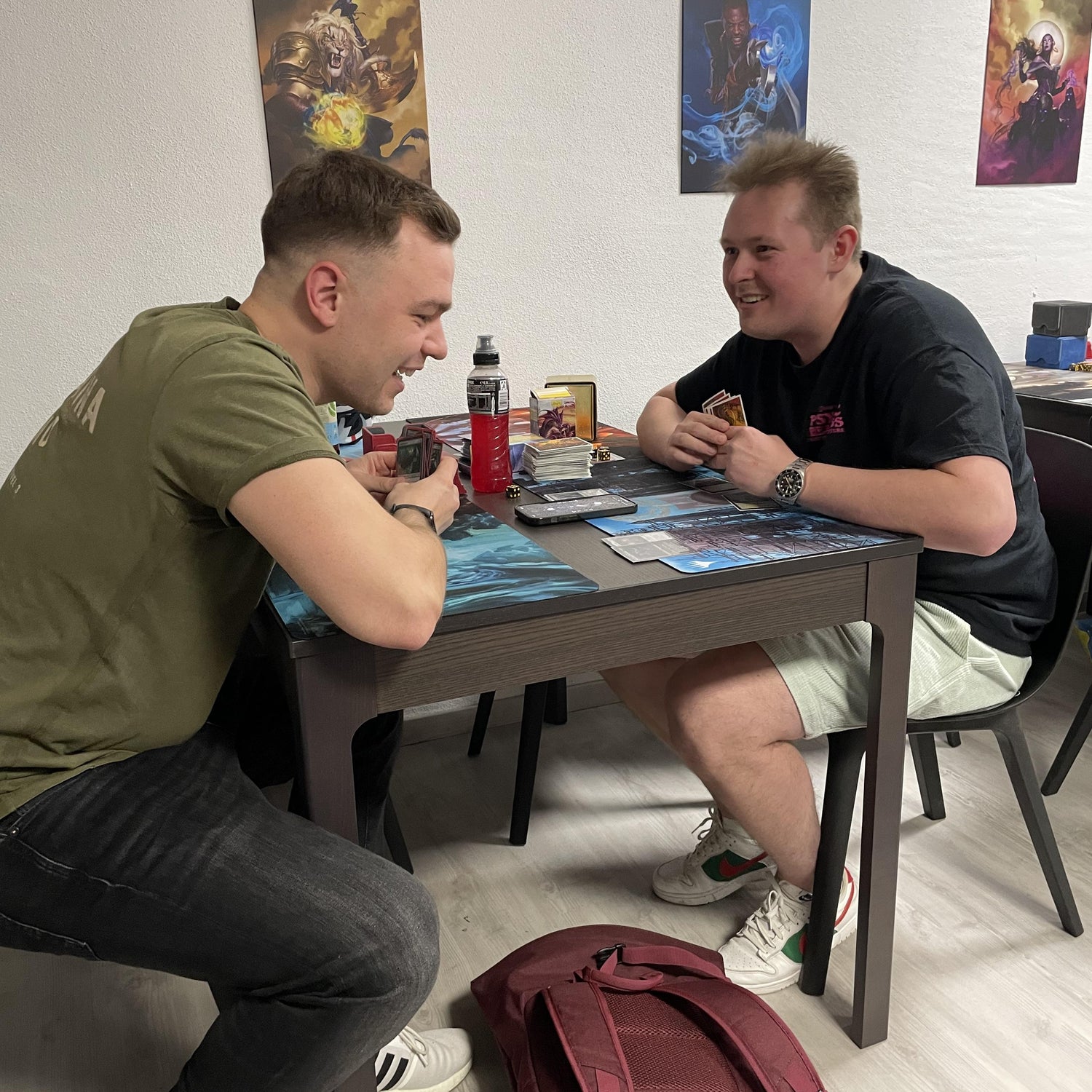 Zwei TCG-Spieler im Trinket Mage Store – gemeinsamer Moment beim Kartenspiel