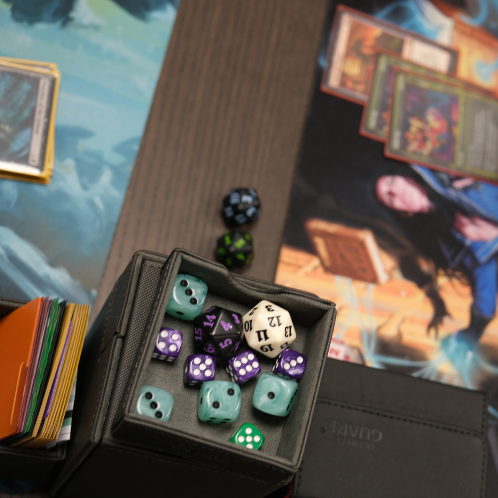 Sammelkartenzubehör mit Würfeln, Deckbox, Karten und Spielmatten für Trading Card Games.