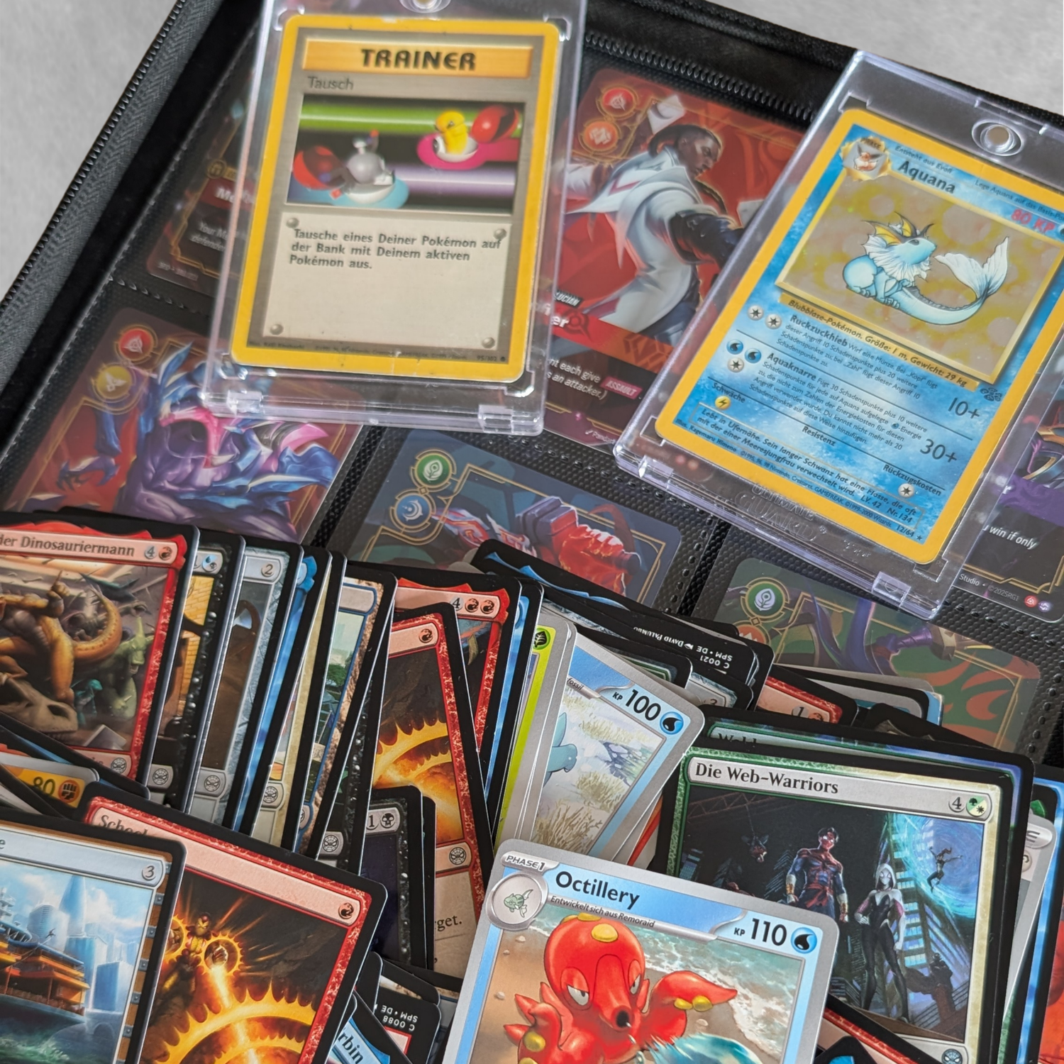 Sammelkarten verschiedener TCGs liegen neben Karten in Toploadern und einem Kartenbinder mit Sammelkartenfächern.